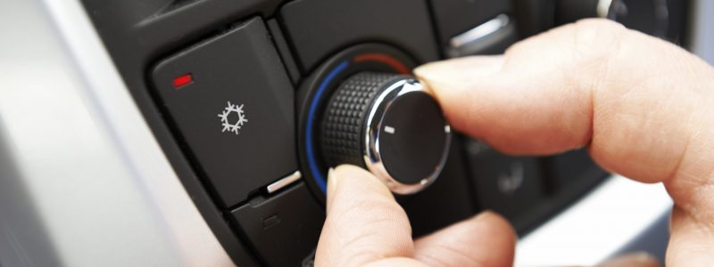 Close Up Of Hand Adjusting Car Air Conditioning Control On Dashboard